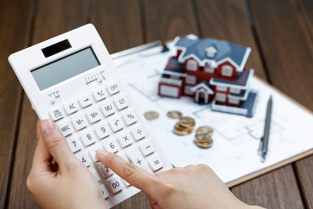/upl/a-female-hand-operating-a-calculator-in-front-of-a-villa-house-model.jpg