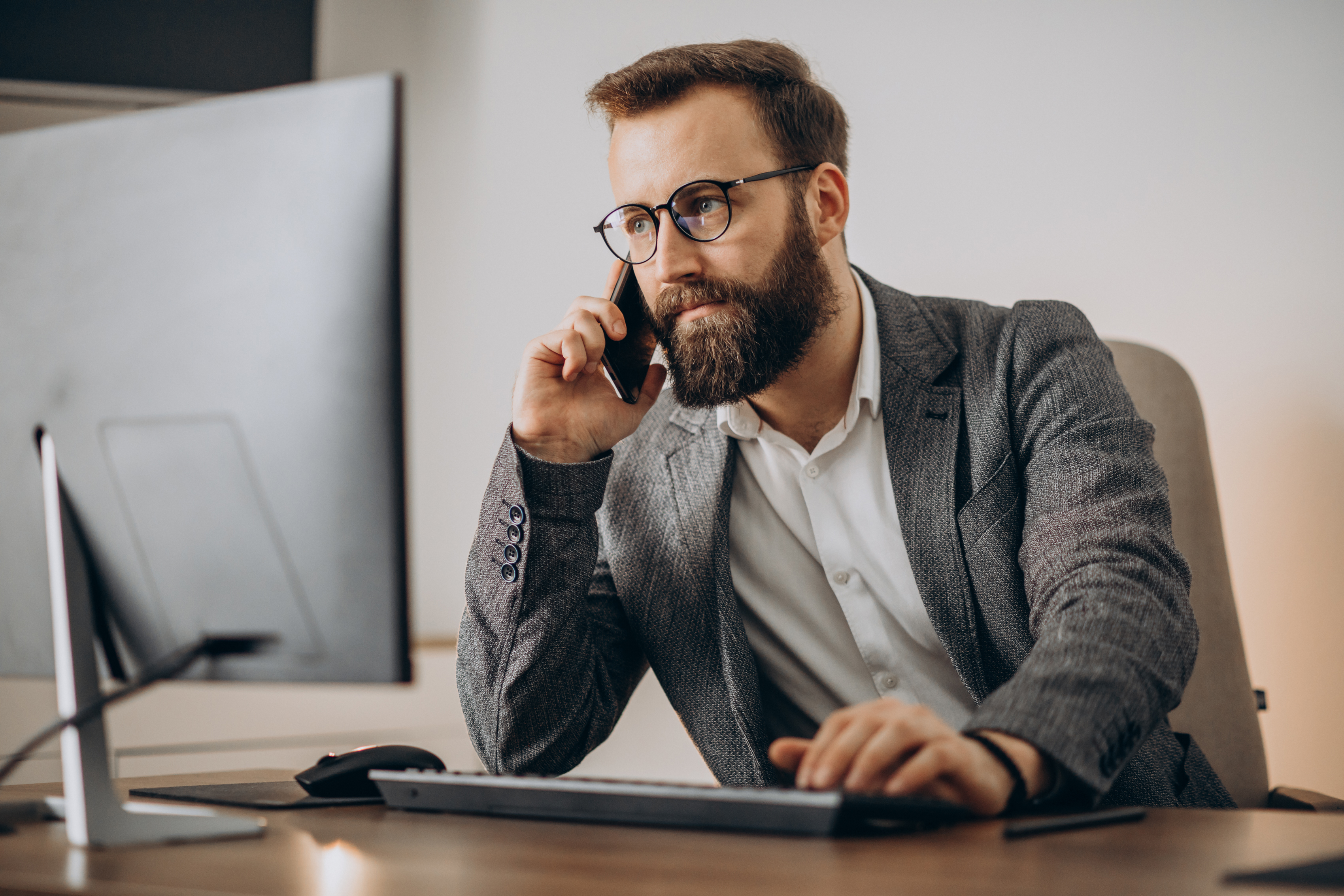 /upl/young-business-man-talking-phone-working-computer.jpg