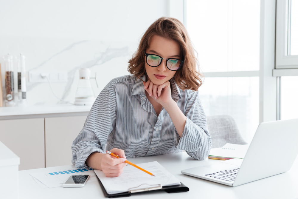 /upl/young-concentrated-businesswoman-in-glasses-and-striped-shirt-working-with-papers-at-home.jpg