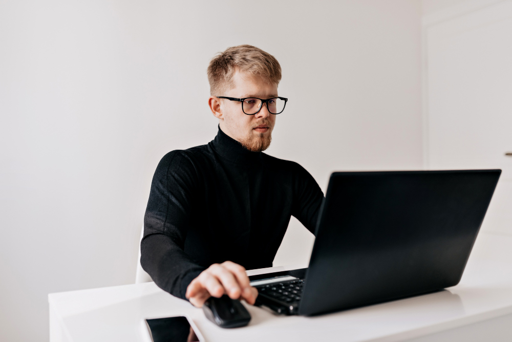 /upl/young-man-team-leader-confident-young-man-working-at-his-desktop-with-laptop-and-looking-with-smile-in-his-light-office.jpg